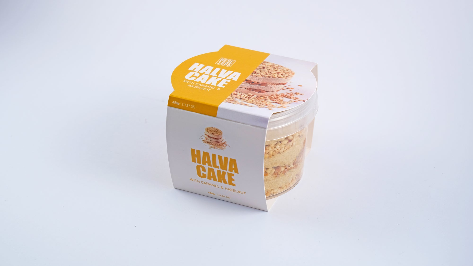 Angled side view of Premium Halva Cake – Caramel & Hazelnut – 450g in clear jar with box sleeve
Schuine zijaanzicht van Premium Halva Cake – Karamel & Hazelnoot – 450g in transparante pot met kartonnen omhulsel
Schräge Seitenansicht des Premium Halva-Kuchens – Karamell & Haselnuss – 450g im transparenten Glas mit Kartonhülle