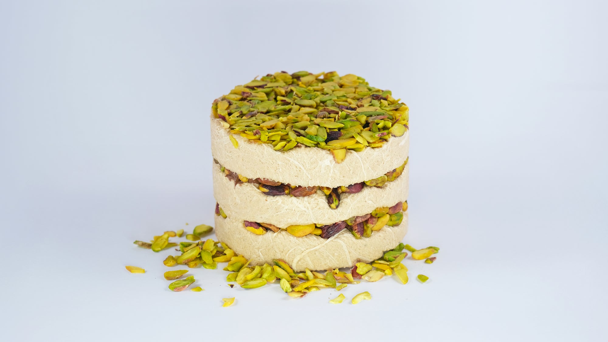 Whole Halva Cake topped with crushed pistachios on plain white background
Hele Halva Cake met gehakte pistachenoten op witte achtergrond
Ganzer Halva-Kuchen mit gehackten Pistazien auf weißem Hintergrund
